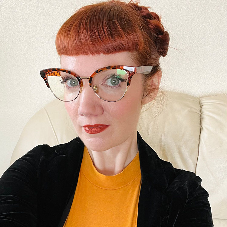 A headshot of a person in a yellow shirt and a black jacket