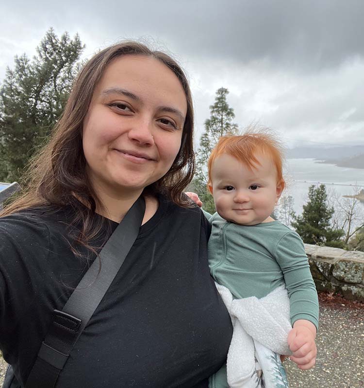 A smiling person holds a young child