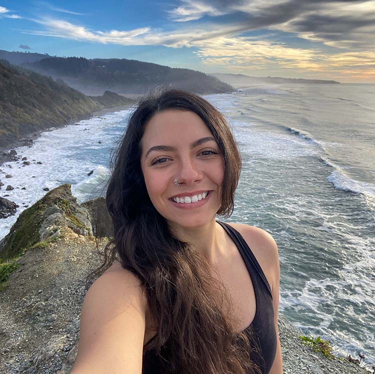 A person takes a selfie on a cliff overlooking the ocean