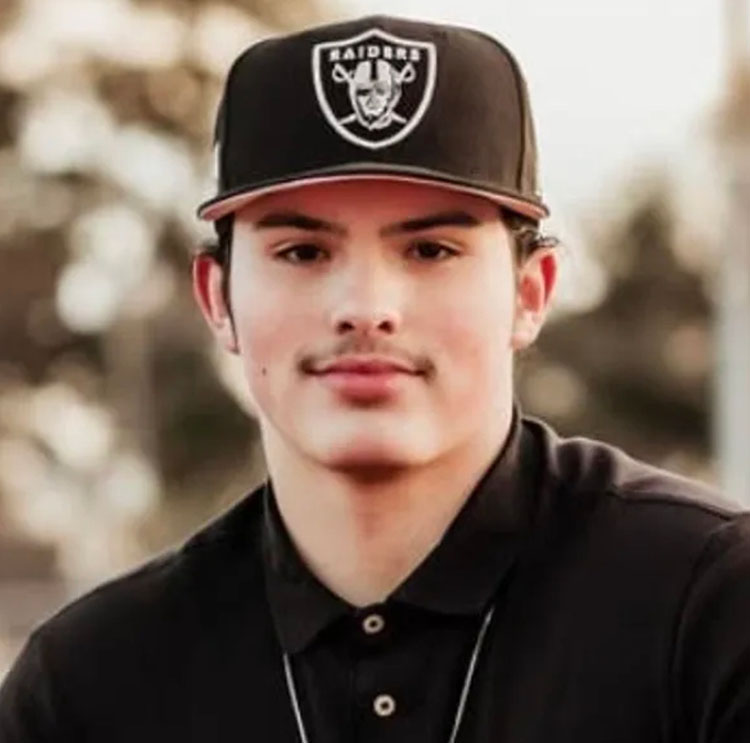 A headshot of a person wearing a nice shirt and a Raiders cap