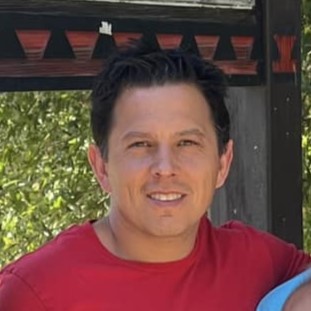 A smiling person stands outdoors