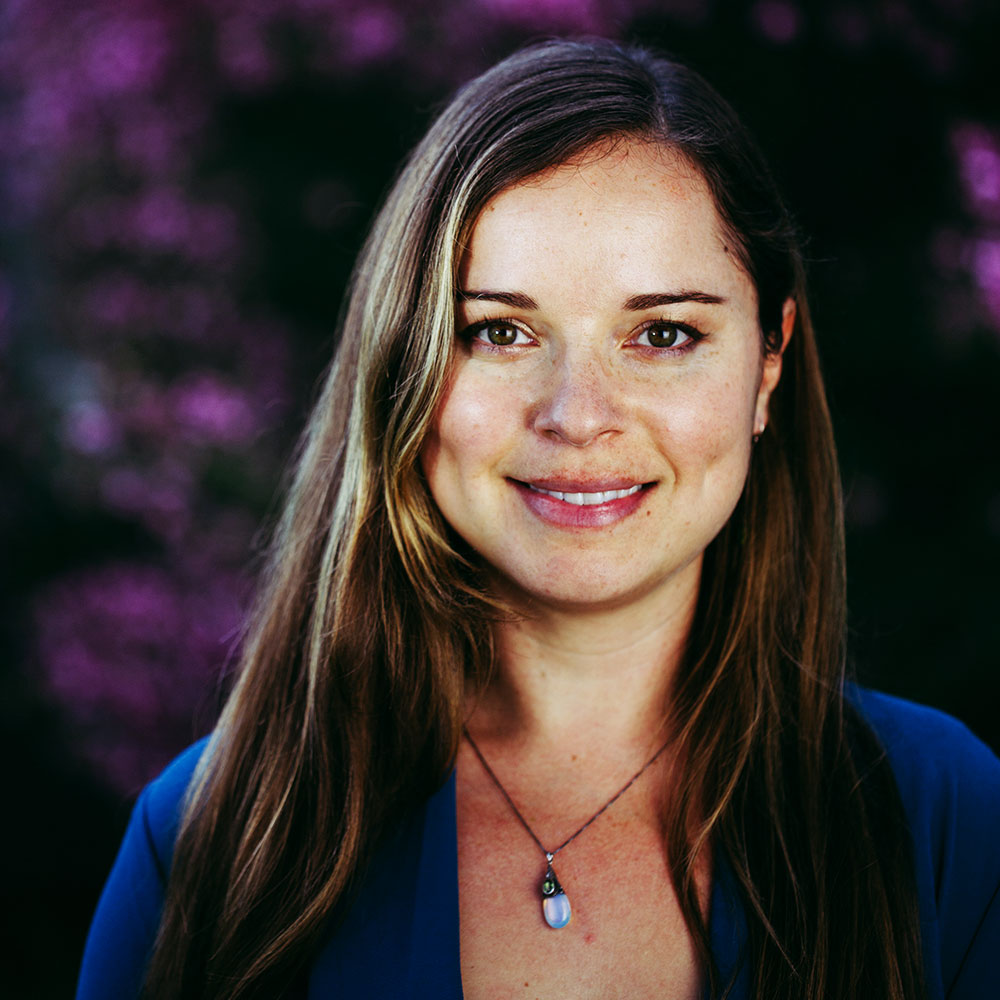 A woman stands in front of some flowers