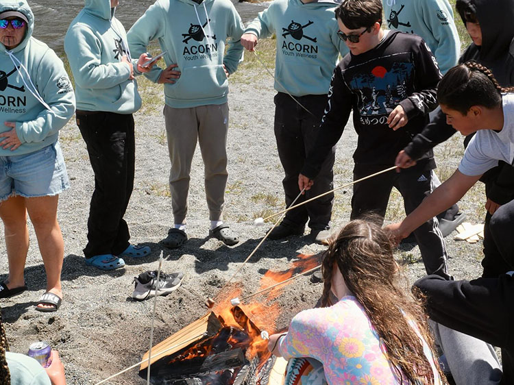 A number of people roast marshmallows on a beach