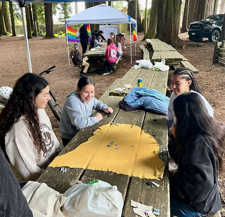 A number of people work together on a picnic bench