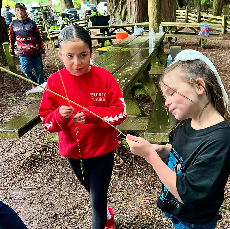 Two younger people work together with some sticks