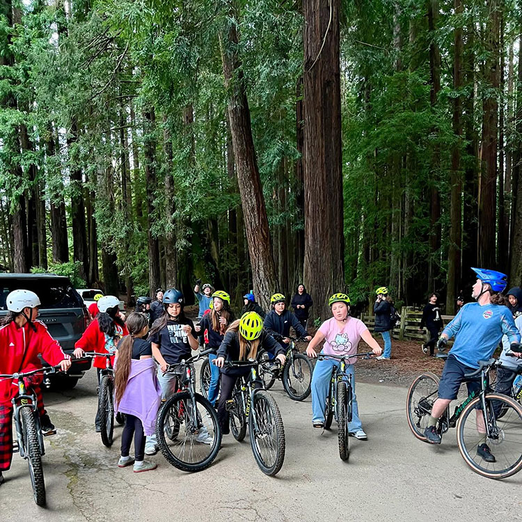 A number of people sit on a road on bikes