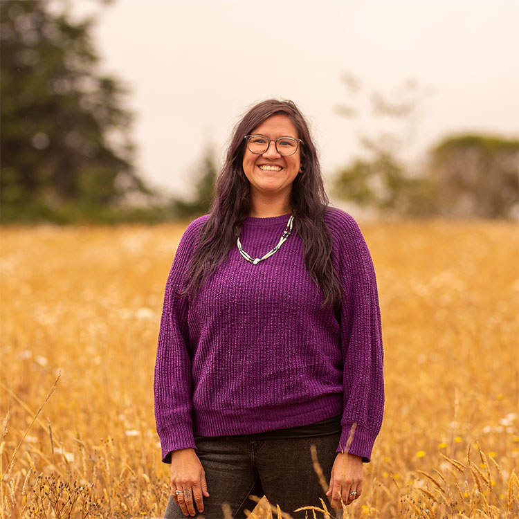 A smiling person stands in a field