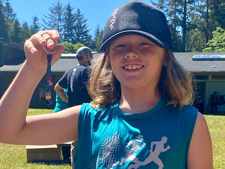 A young adult holds up a keychain and smiles