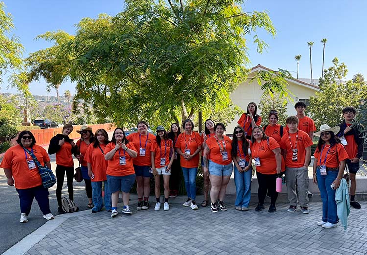 A group of young adults pose for a photo in matching shirts