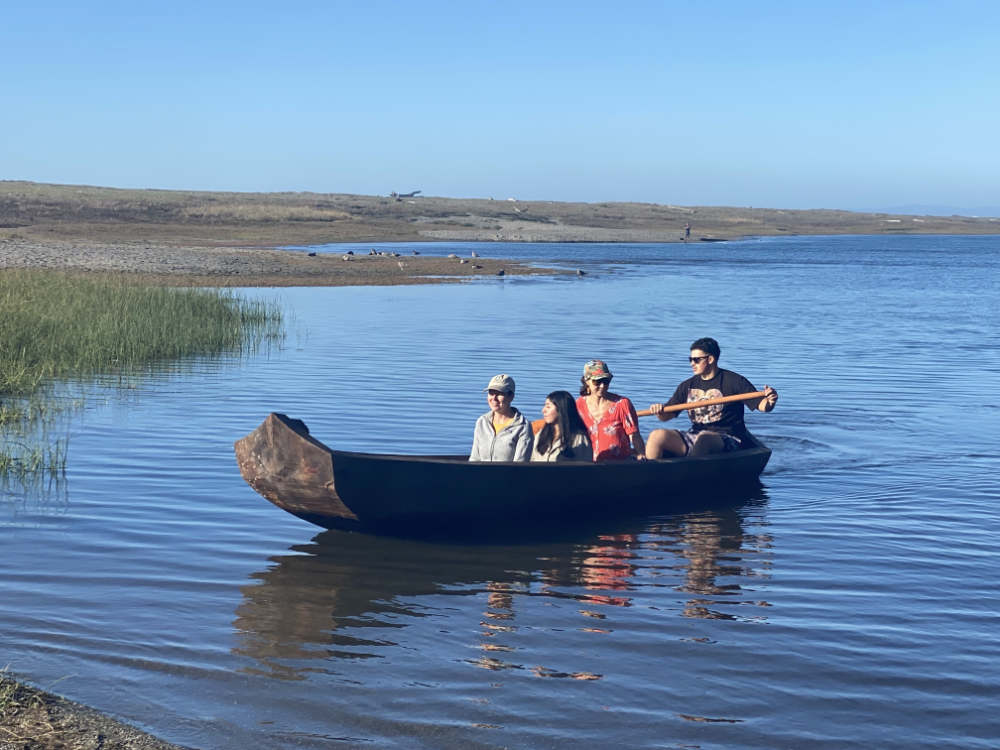 Several people ride in a traditional canoe on a lake