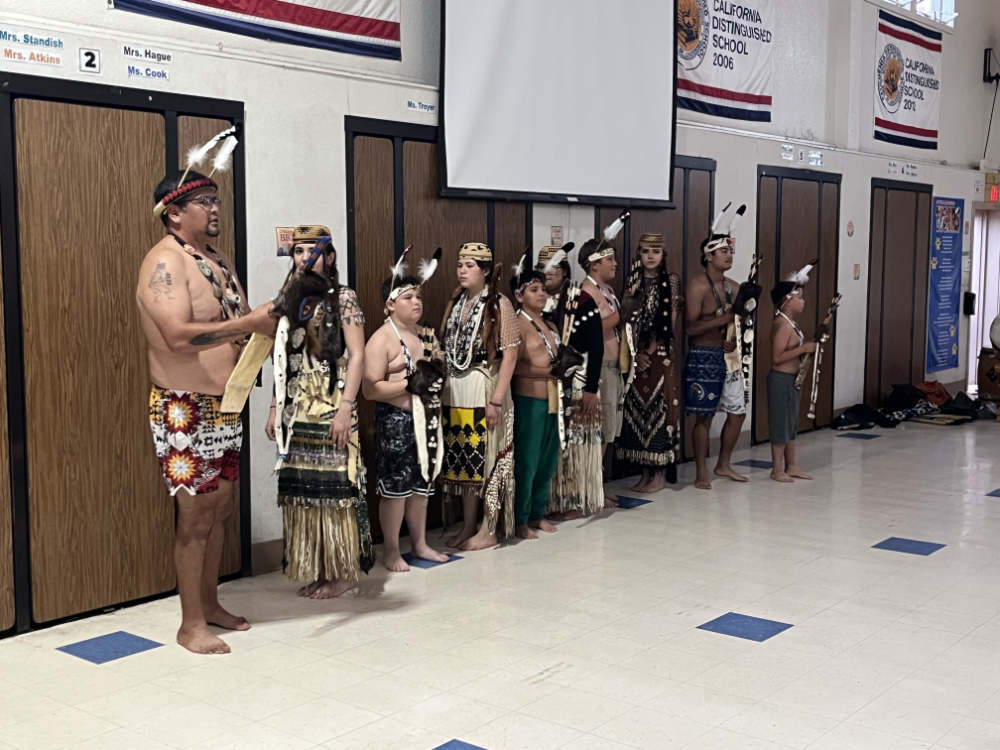 A number of young adults stand in a line in traditional dress