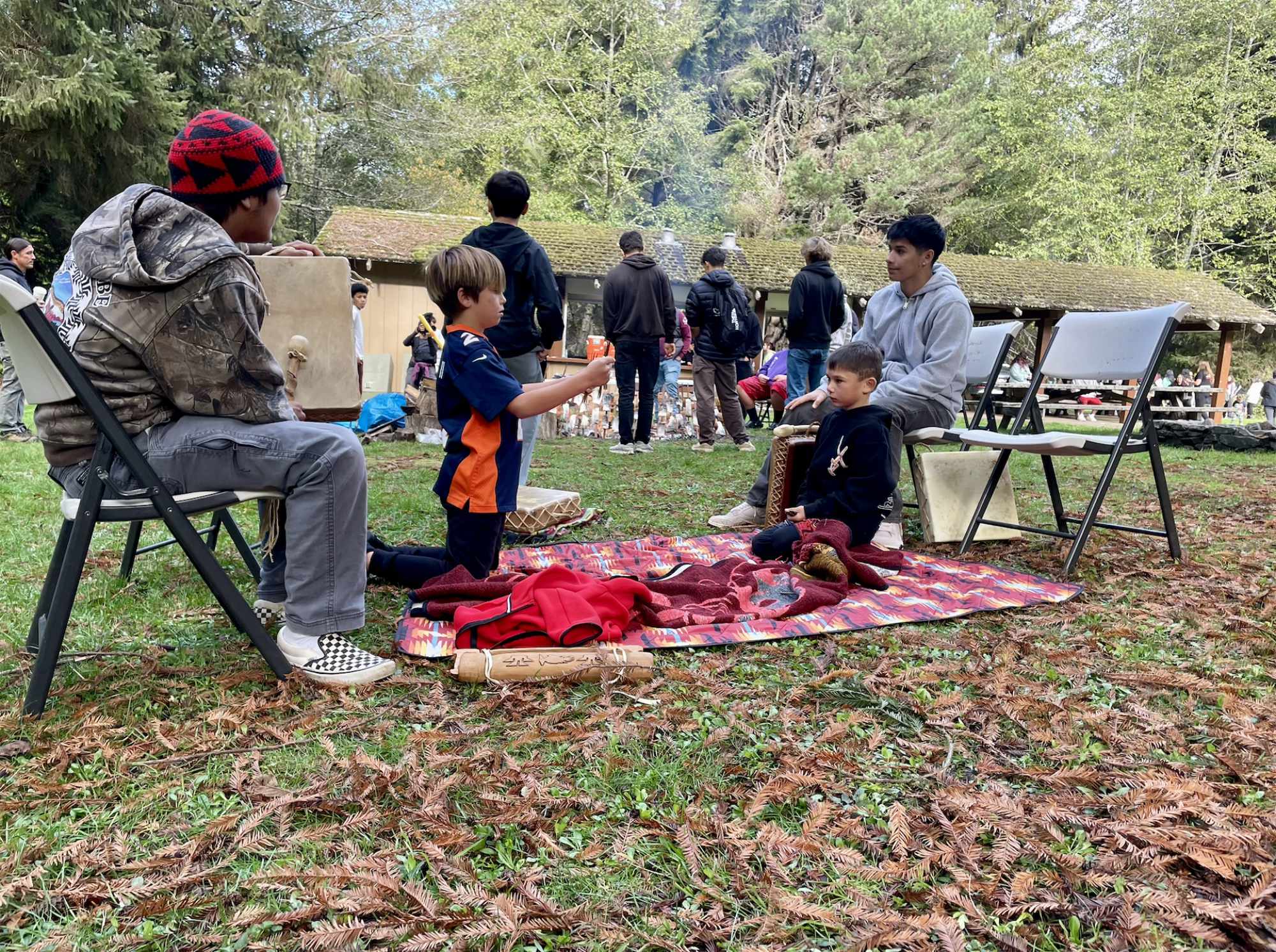 A group of youth and adults lounge in a forested area