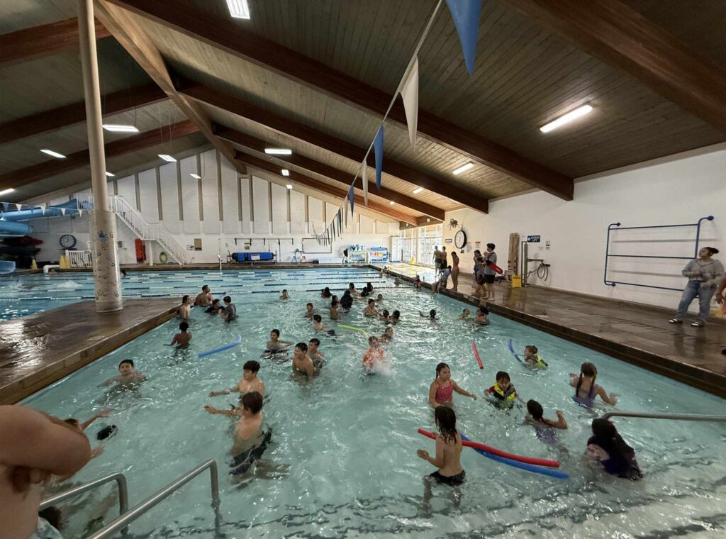 A group of young adults play in a pool together