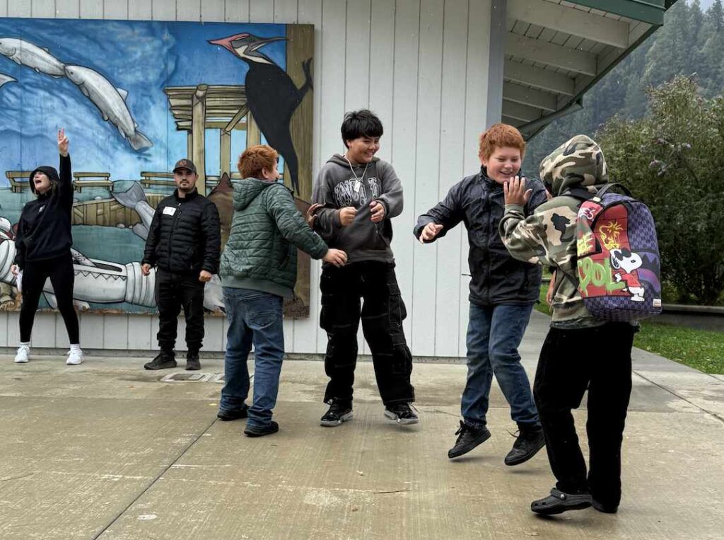 A group of youth play together outside of a school