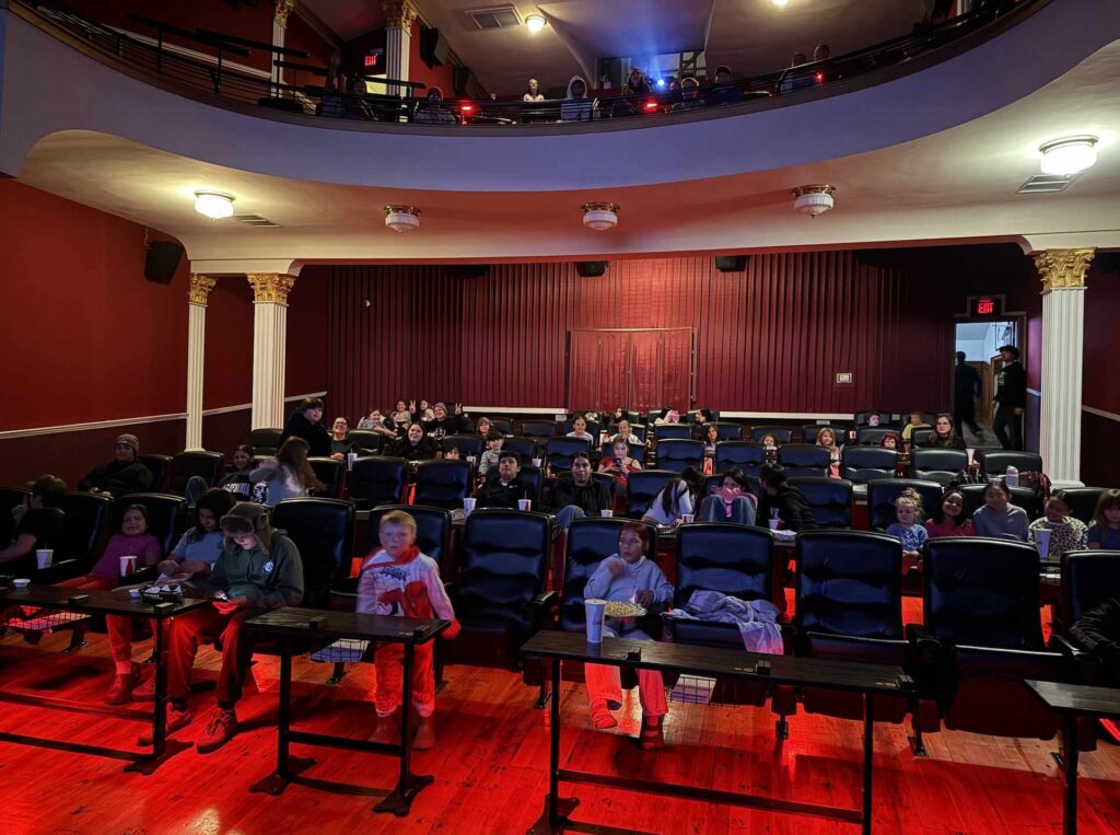 A photo of a movie theater with a number of youth in the seats