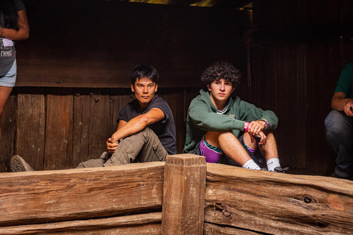 Two young adults sit in a traditional lodge