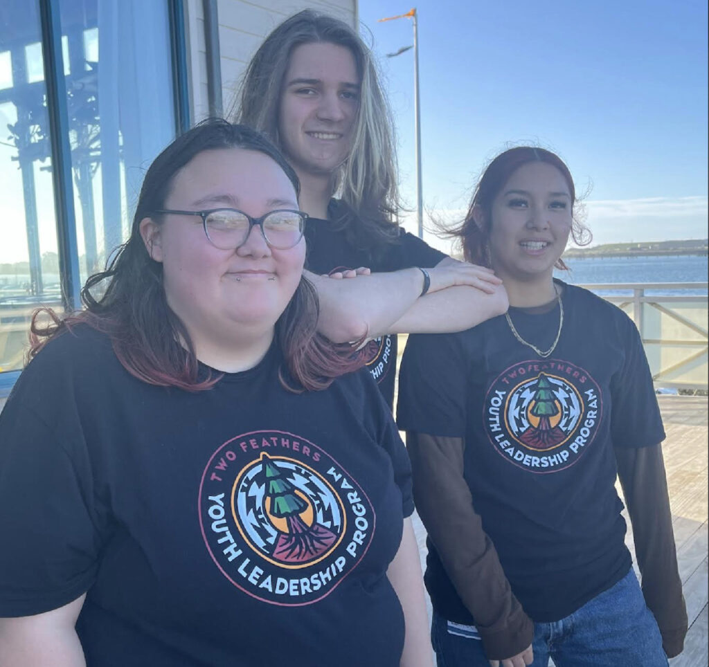 Three people stand outside and pose for the camera