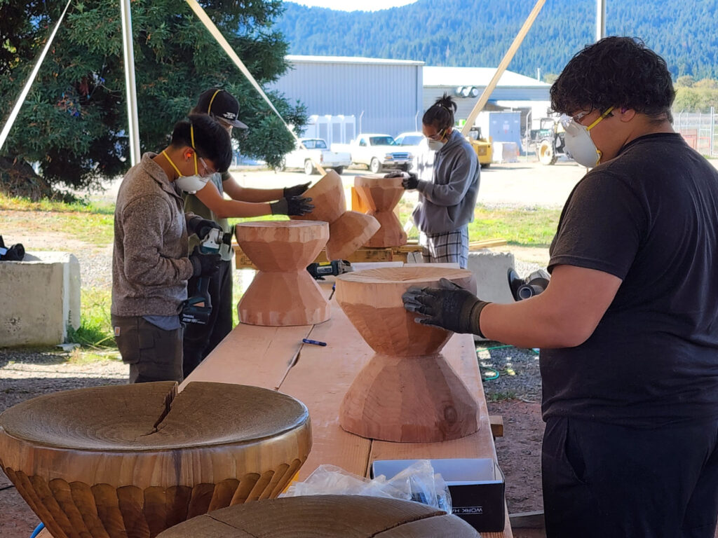 Four people work on assembling items outdoors