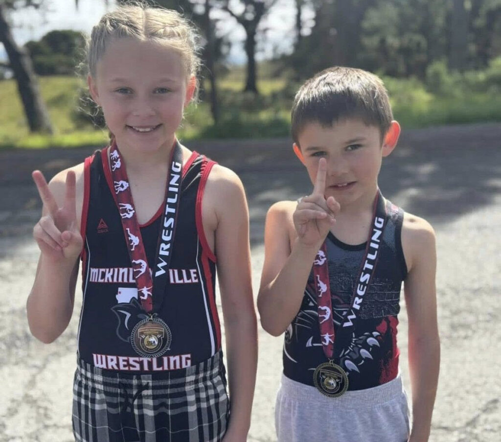 Two young children with wrestling awards pose for the camera